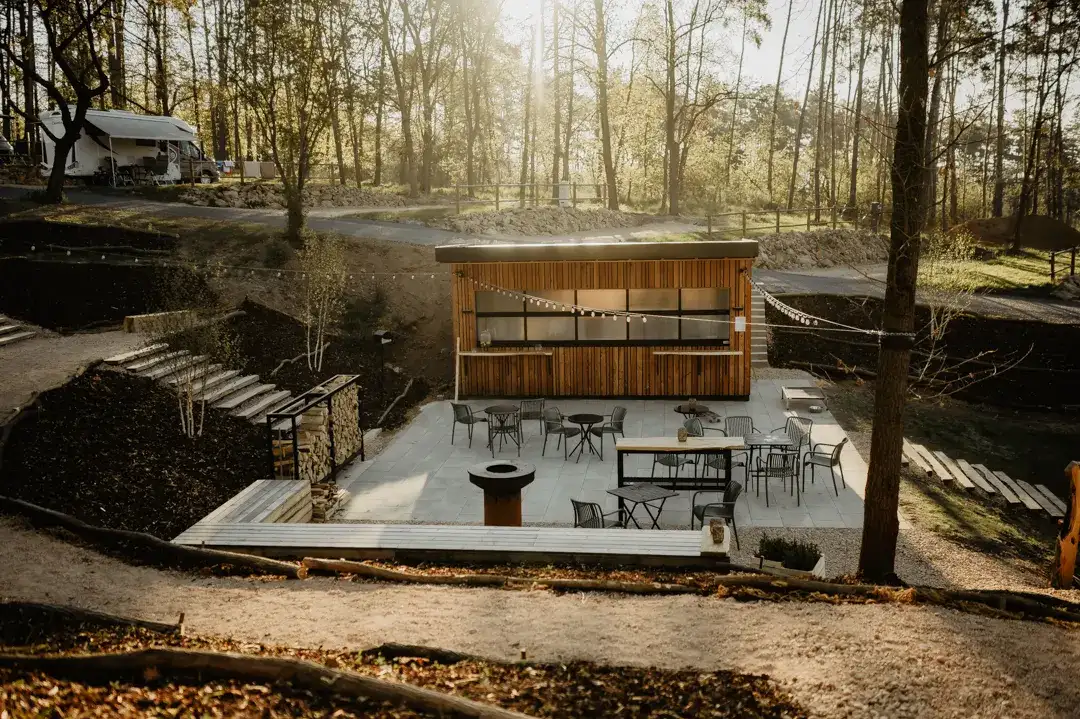 Guests at a fire pit and seating in the campsite's natural setting.