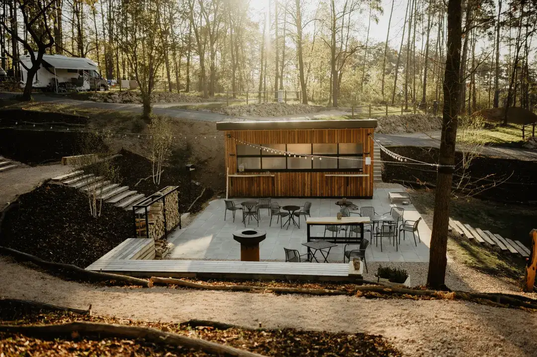 Guests at a fire pit and seating in the campsite's natural setting.
